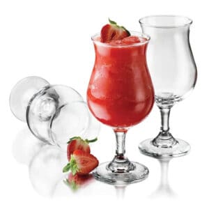 Fresh strawberry smoothie in a tall glass with ice, strawberries, and clear glassware on a white background.