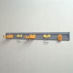 Clothes hanging hooks and rail on a plain wall, used for organization and laundry purposes in commercial or residential spaces.