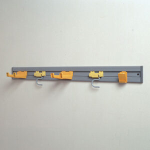 Clothes hanging hooks and rail on a plain wall, used for organization and laundry purposes in commercial or residential spaces.