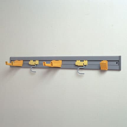Clothes hanging hooks and rail on a plain wall, used for organization and laundry purposes in commercial or residential spaces.