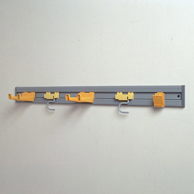 Clothes hanging hooks and rail on a plain wall, used for organization and laundry purposes in commercial or residential spaces.