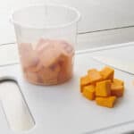 Food safety practices with chopped cheese in a container and on a cutting board, emphasizing hygiene standards in kitchen environments.