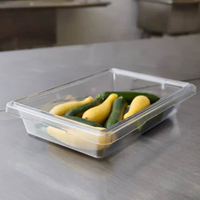 0041300_2.jpg Fresh yellow and green finger cucumbers stored in a clear plastic container on a stainless steel surface.