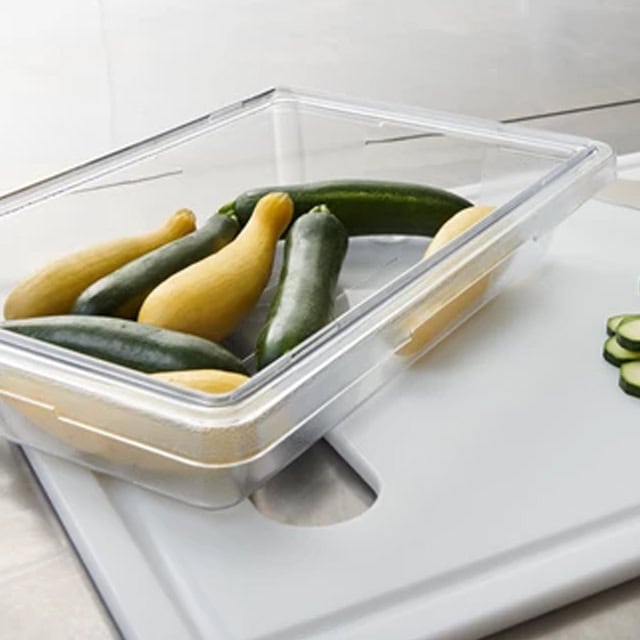 0041300_3.jpg Fresh zucchinis stored in a clear plastic container, ready for kitchen use, emphasizing hygiene and freshness.