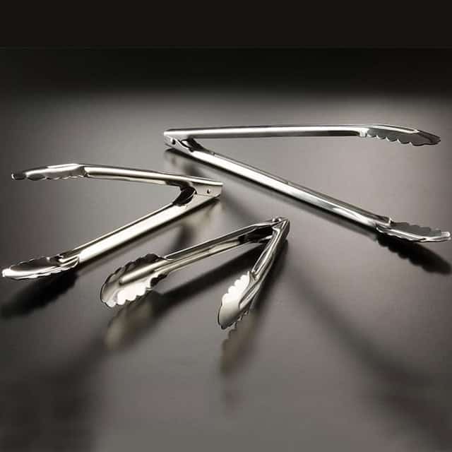 0047428_1.jpg Stainless steel tongs on a dark surface, ideal for food handling and hygiene.