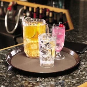 Refreshing colorful beverages on a dark granite bar counter, featuring a cocktail with a cherry garnish, perfect for a vibrant social setting.