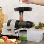 Freshly made green juice extracted using a juicer with visible fruits and vegetables around, showcasing healthy living and food safety.