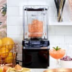 Blender with frozen fruit for smoothies in a modern kitchen setting, emphasizing healthy eating and beverage prep.