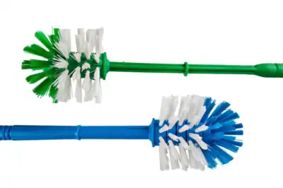 Green and blue disposable toilet brushes with white cleaning bristles, ideal for hygiene and sanitation, displayed against a white background for commercial cleaning solutions.