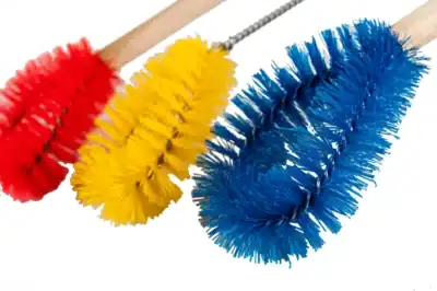 Red, yellow, and blue cleaning brushes with long bristles for sanitation and hygiene cleaning tasks.