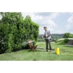 Pressure washing outdoor garden furniture with a power washer in lush green garden.
