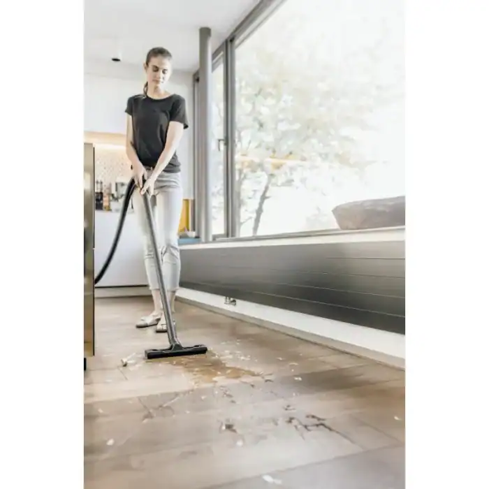 Vacuum cleaner cleaning spilled liquid on hardwood floor at home, professional hygiene service.