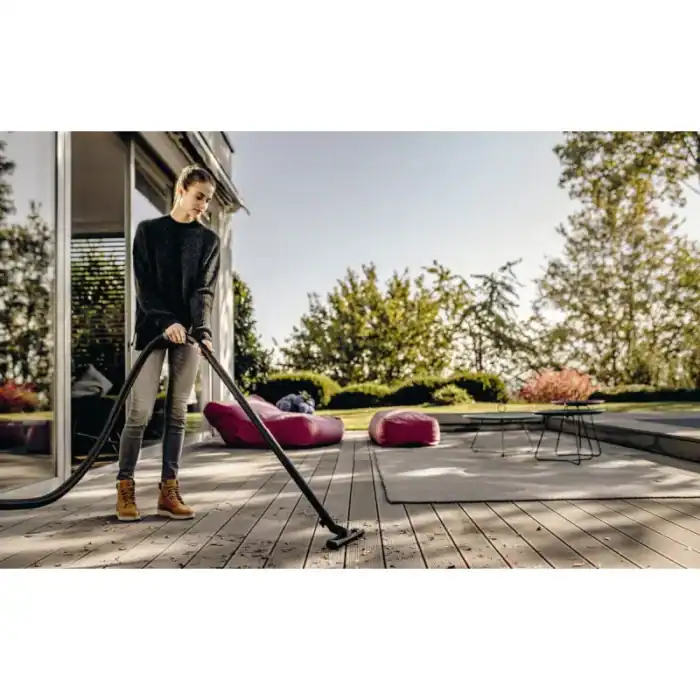 High-pressure outdoor vacuum cleaning on wooden patio, woman using suction device for deck cleaning, modern home exterior, clean outdoor space, beyond hygiene asia.