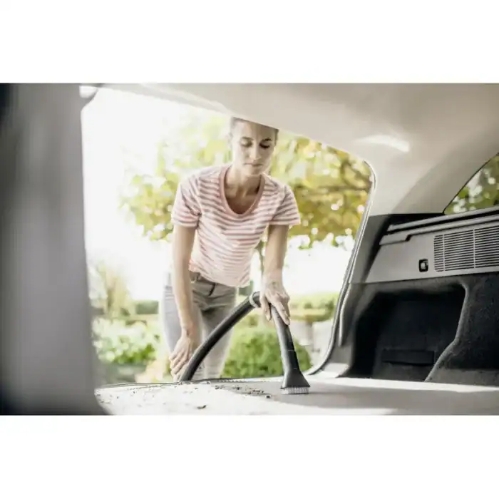 Vacuum cleaner being used to clean car trunk outdoors, professional cleaning service, beyond hygiene asia, vehicle sanitation, eco-friendly cleaning solution, high-quality hygiene maintenance, car interior cleaning service.