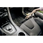 Accumulation of dirt and debris in a car interior vacuumed by a child, highlighting the need for professional car cleaning services.