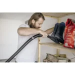 Vacuuming storage shelf with a canister vacuum cleaner and firewood, home cleaning in progress, organized home maintenance scene, Beyond Hygiene Asia.