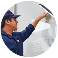Window cleaning professional in uniform washing glass with squeegee in a commercial building.