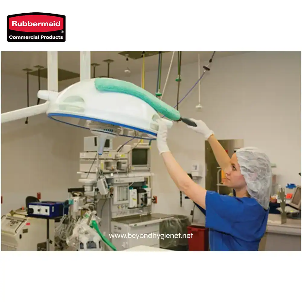 2 Large surgical light being installed or maintained by a healthcare professional in a sterile medical environment with advanced medical equipment in the background.
