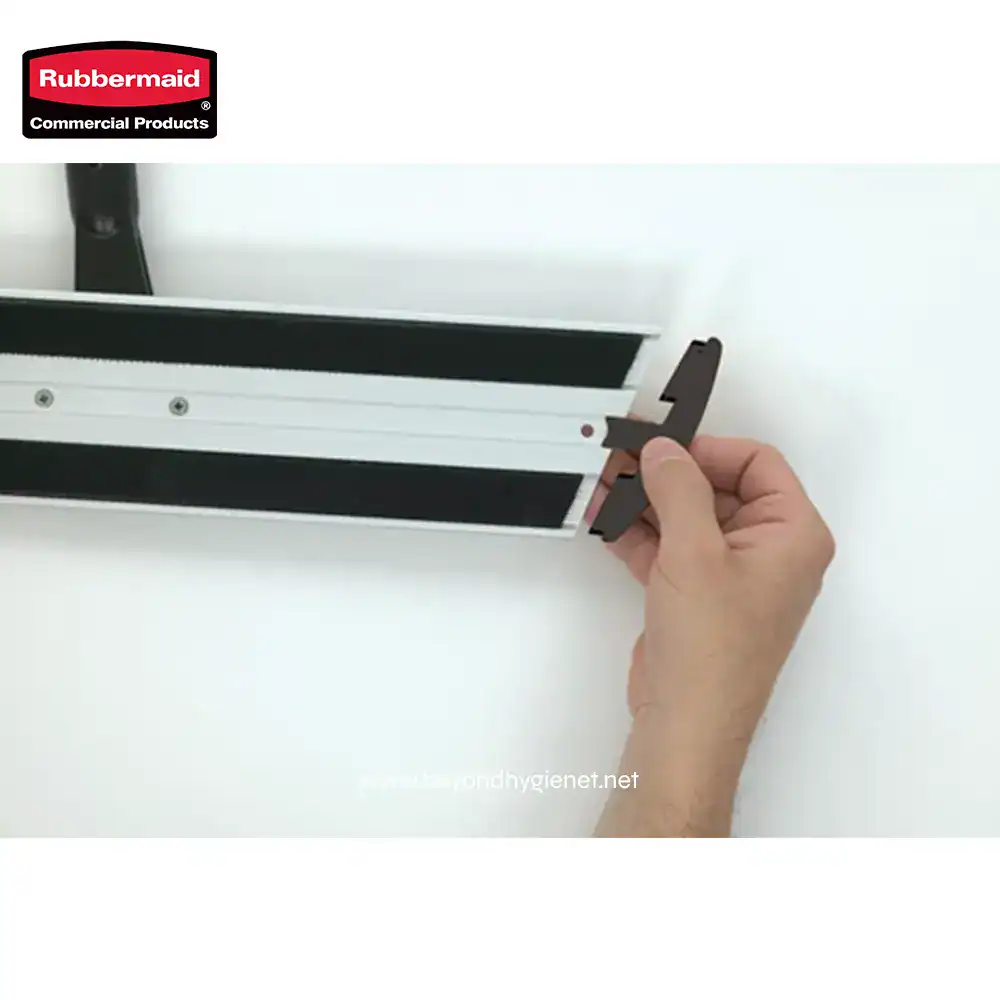 3 Rubbermaid commercial cleaning tool, plastic and metal component assembly, close-up of hand installing or repairing a hygienic cleaning product, demonstrating maintenance or setup.