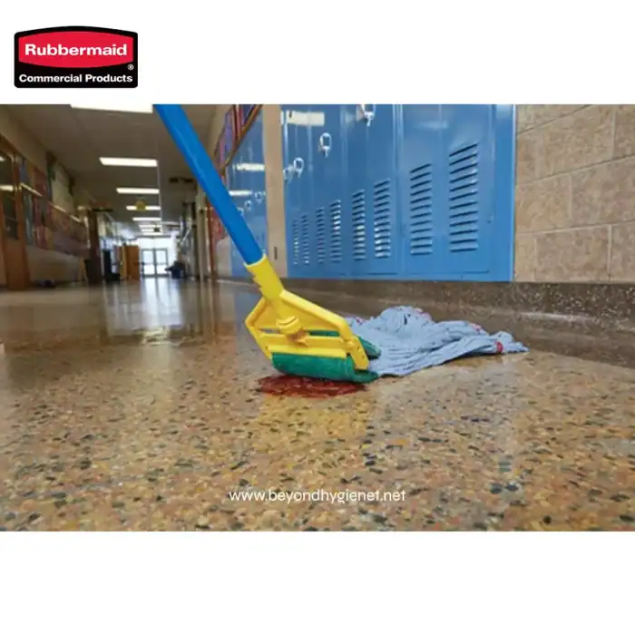 Rubbermaid commercial cleaning mop and cloth on speckled tile floor in school hallway.