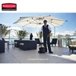 Cleaning staff discarding debris on outdoor terrace with seating and umbrellas, maintaining hygiene standards at a hospitality or commercial venue.