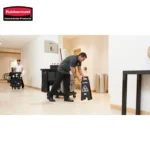 Cleaning staff performing floor sanitation with wet floor caution sign in a commercial building.