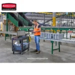 Rubbermaid commercial products in industrial warehouse, employee inspecting equipment, conveyor belts, and safety gear for hygiene and safety compliance.