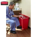 Red medical waste disposal bin in a healthcare setting, used for proper disposal of sharps and contaminated materials to maintain hygiene and safety.