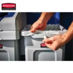 Rubbermaid commercial trash waste bin with hands changing trash bag for sanitation and waste management. industrial trash container used in hygiene and cleaning solutions.