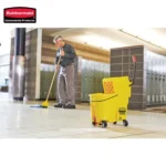 Rubbermaid commercial janitorial equipment, cleaning staff mopping tiled floor in modern facility, yellow cleaning cart with mop bucket and tools, professional cleaning service, hygiene maintenance in public spaces.