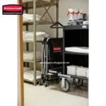Rubbermaid commercial cleaning cart with cleaning supplies, towels, and equipment in a hygiene closet.