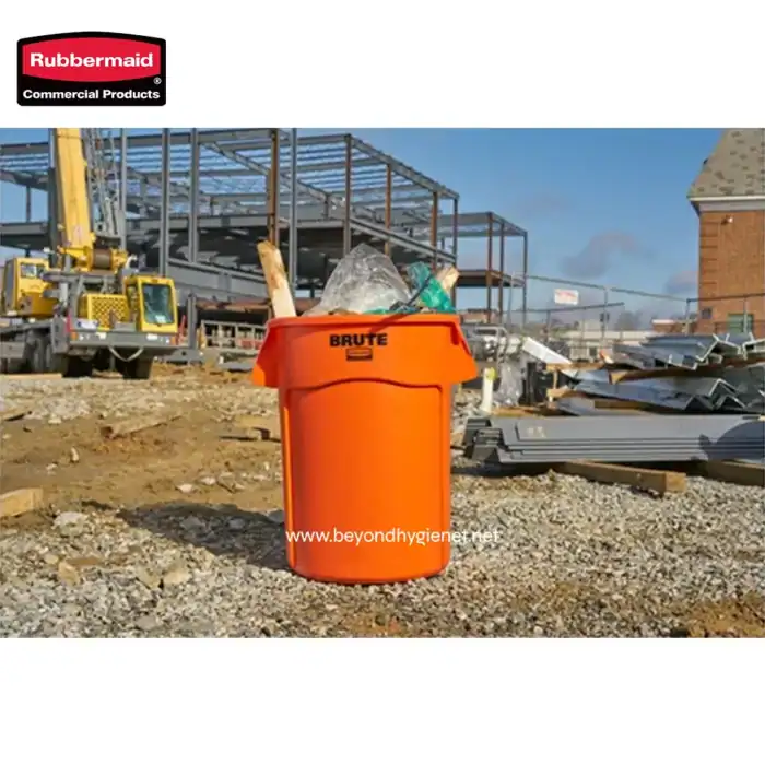 Orange construction waste bin on construction site with steel framework and debris, emphasizing waste management and safety, part of Beyond Hygiene Asia's sanitation solutions for construction environments.