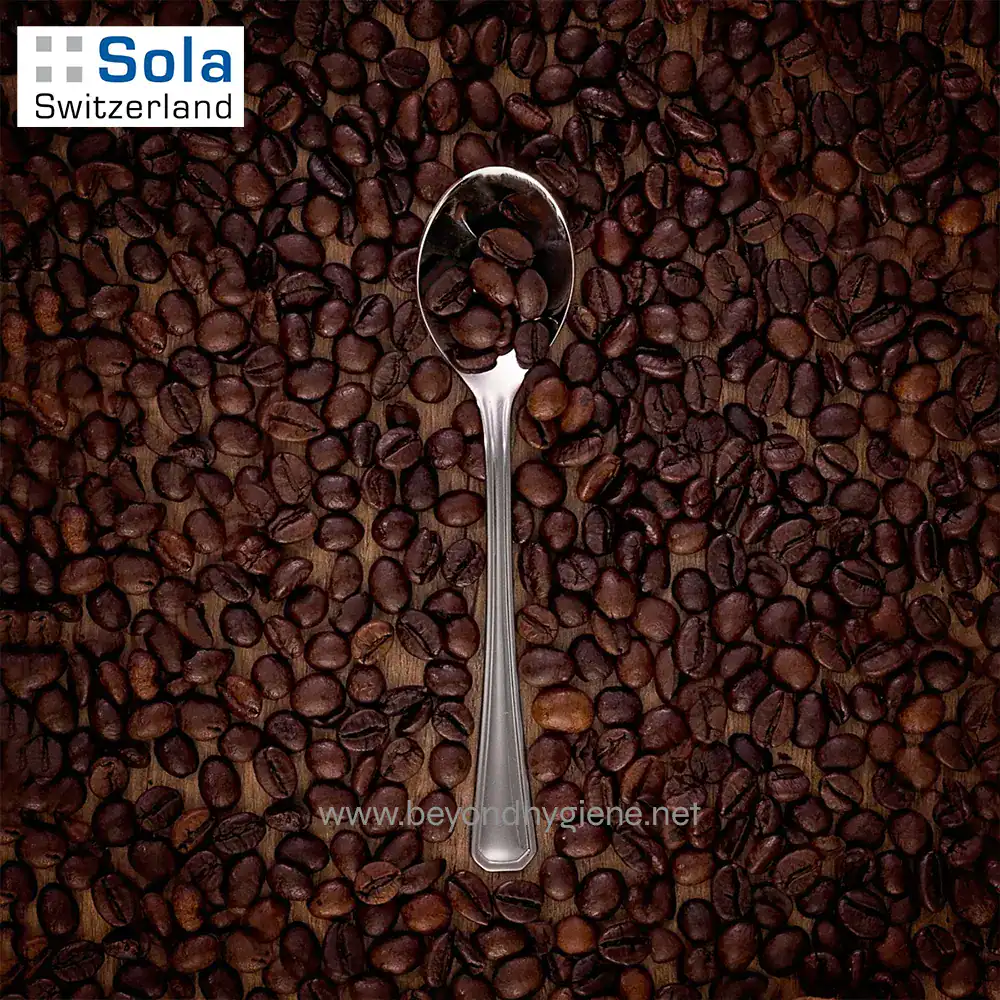 OSLO 1810 Stainless Steel-4 Coffee beans with a metal spoon on a wooden surface, close-up shot for coffee shop or beverage business SEO.