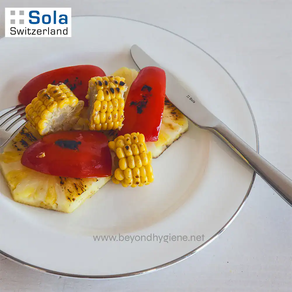 TURIN 1810 Stainless Steel-4 Grilled pineapple and vegetable salad on white plate with fork and knife, healthy vegetarian dish, fresh grilled produce, Beyond Hygiene Asia, Sola Switzerland.