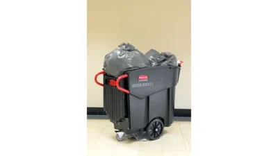 Heavy-duty waste bin with large black trash bags, mobile wheels, and red handles, suitable for commercial or industrial cleaning.