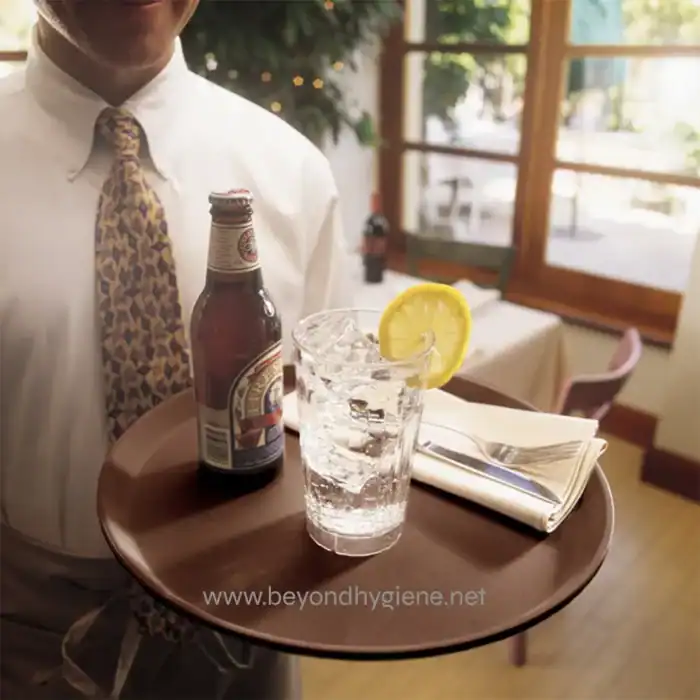 Refreshing drink with lemon slice on ice glass served in restaurant, with a beer bottle nearby, hospitality and food service setting.