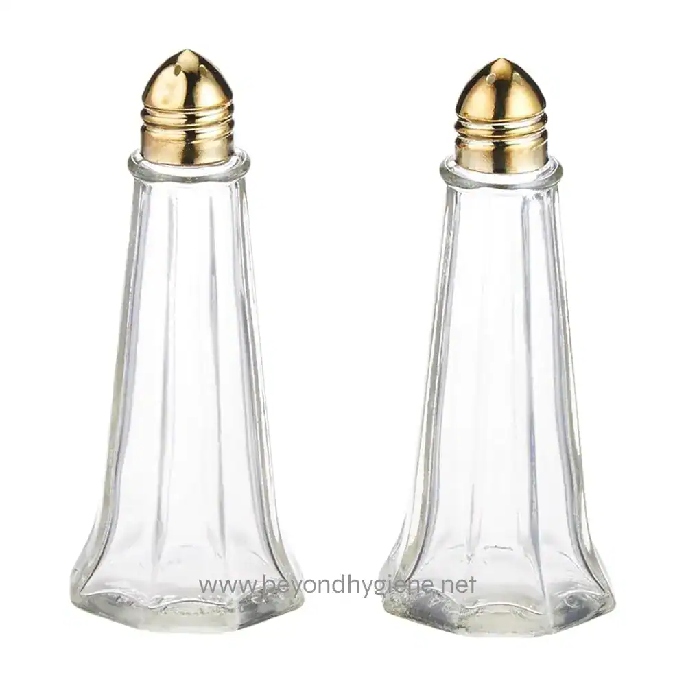 Glass salt and pepper shakers with gold accents, perfect for restaurant or home dining, showcasing hygiene and elegance in table setting.