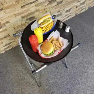 Hot dog with mustard and relish, French fries, cheeseburger, ketchup, mustard, salt, and pepper shakers on a black tray at Beyond Hygiene Asia.