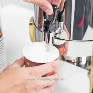 Efficient commercial coffee machine dispensing hot coffee into a paper cup at Beyond Hygiene Asia.