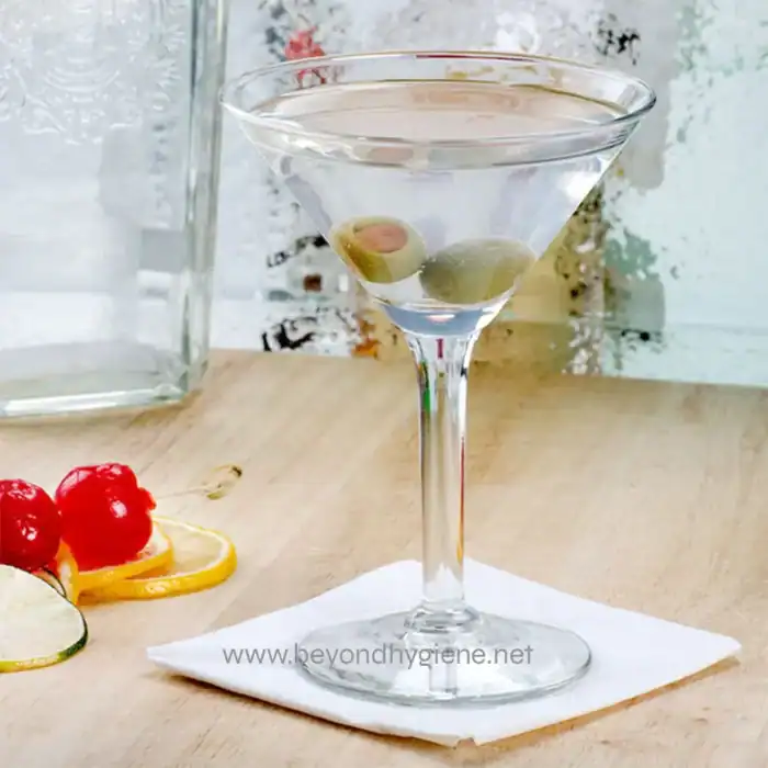 Clarity martini with olives and lemon garnish on a wooden table, showcasing clean and hygienic beverage presentation in a professional setting.
