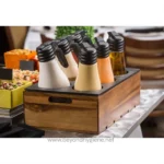 Assorted salad dressings and condiments in squeeze bottles on a wooden tray at a buffet station.