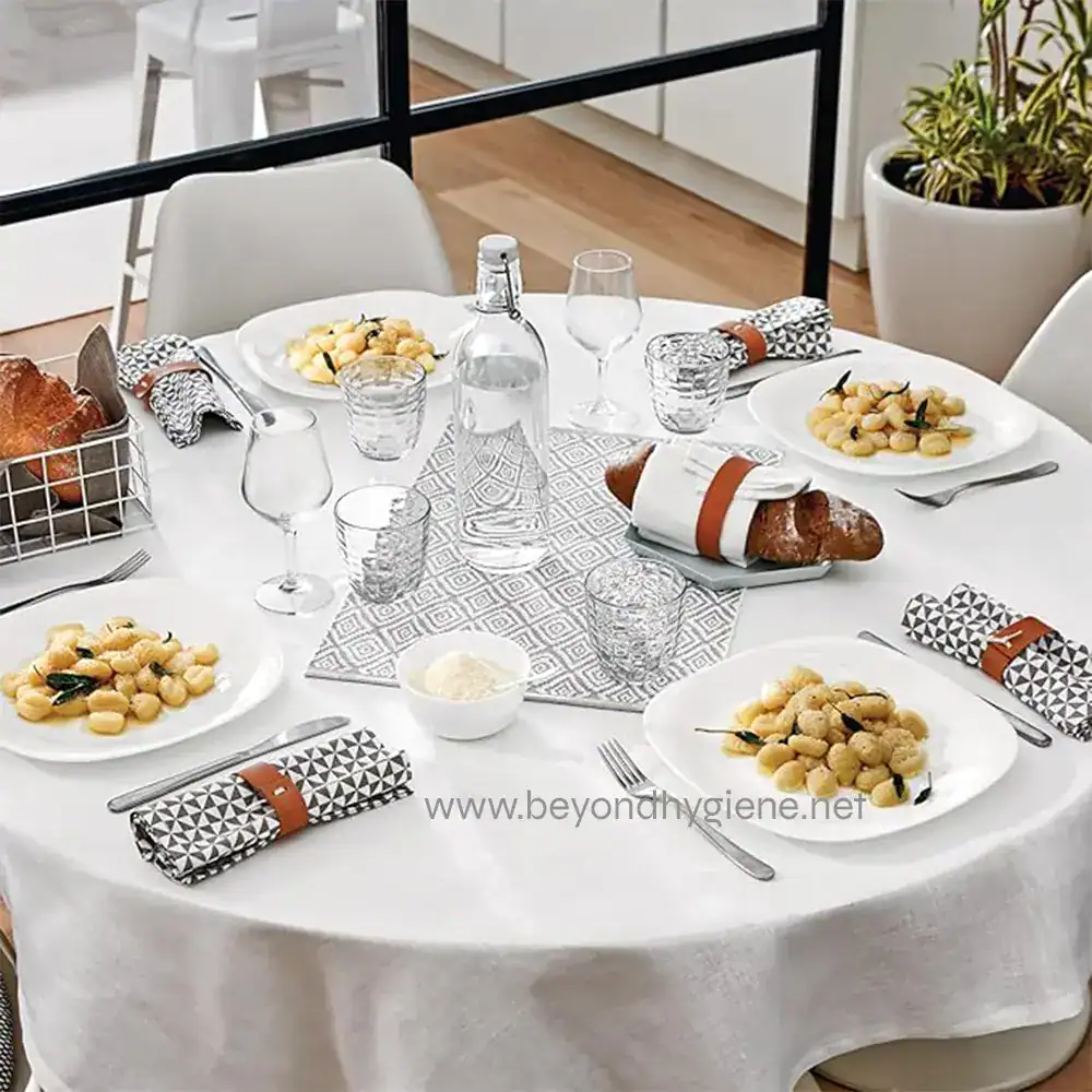 4 Elegant dining table set for a meal with white plates, cutlery, wine glasses, and napkins, in a modern, clean environment emphasizing hygiene and sanitation.