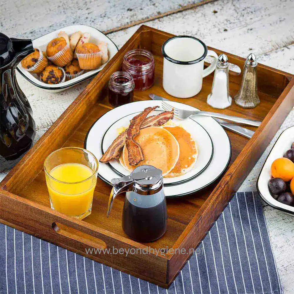 4 Steak and eggs breakfast served on a wooden tray with orange juice, bacon, pancakes, and condiments for a hearty morning meal.