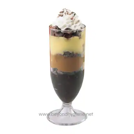 Rich layered dessert in a tall glass with chocolate, caramel, vanilla, and whipped cream, showcasing premium quality and hygiene standards in food presentation.