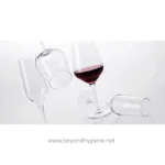 Clear wine glasses, one filled with red wine, with a minimalist and elegant background, representing beverage service and quality hospitality in Asia.