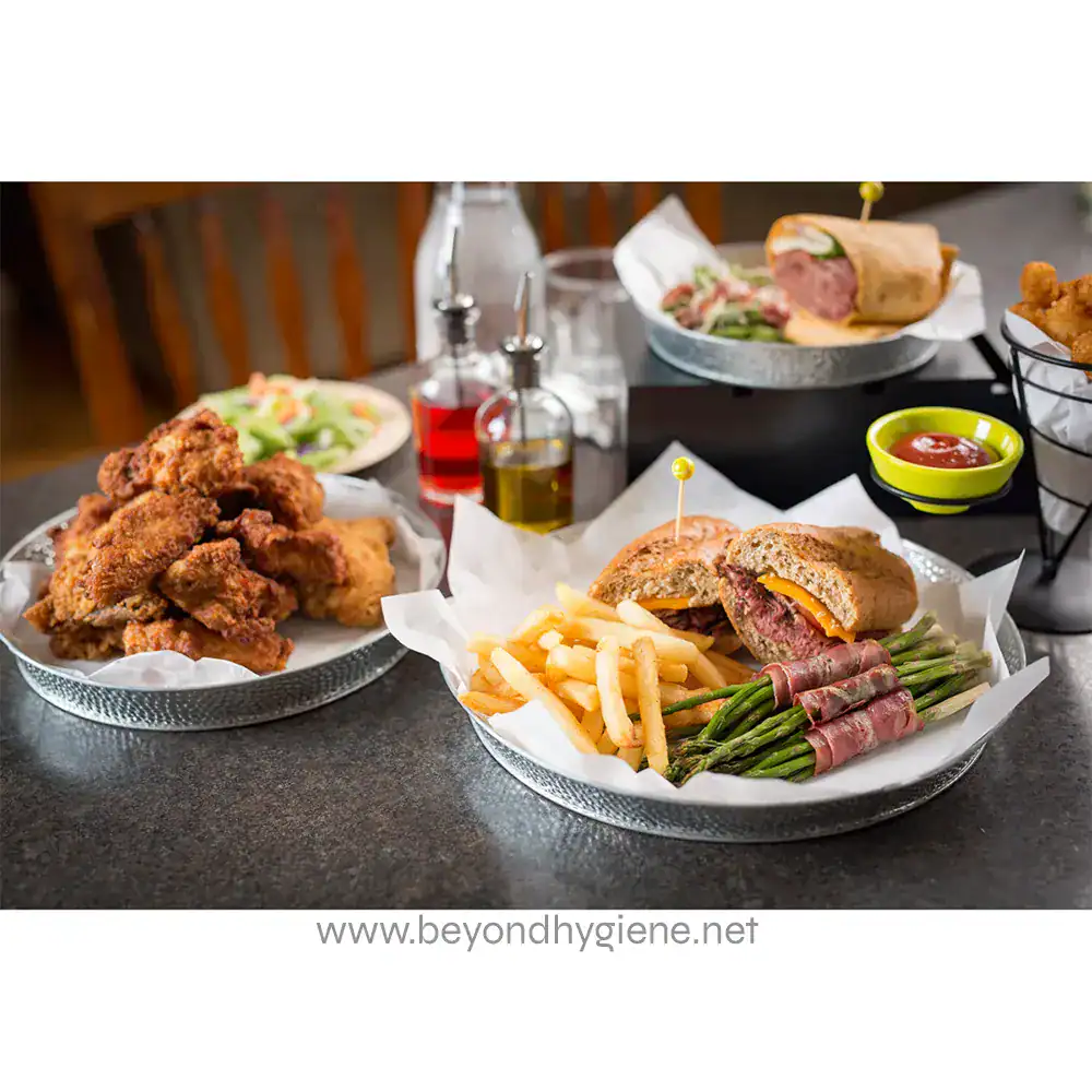 6 Crispy fried chicken, gourmet burger, and fresh vegetables on metal trays with condiments and drinks at Beyond Hygiene Asia restaurant.
