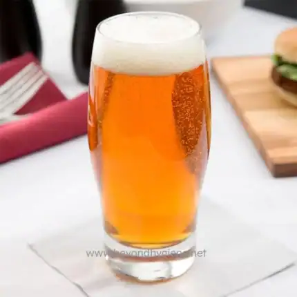 Crisp, refreshing beer served in a tall glass, with bubbles and a foamy head, ideal for social gatherings and celebrations. Perfect for promoting hospitality and food service hygiene.