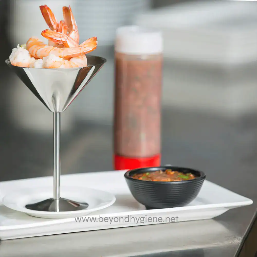 7 Fresh shrimp cocktail served with cocktail sauce on a metal platter, featuring a modern presentation, in a clean kitchen setting.