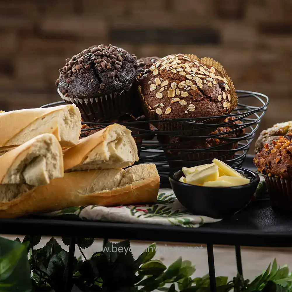 7 Chocolate muffins with toppings including oats and chocolate chips, served with bread and butter on a black tray, promotional image for Beyond Hygiene Asia.