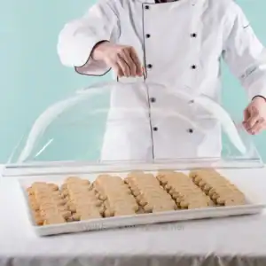 Cookies displayed in a bakery setting under a glass cover in the image.